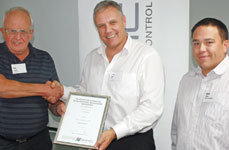 Eric Carter (left) presents Ernst with the SAIMC certificate while Alvin Seitz looks on.